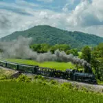 Aerial View of a Narrow Gauge Steam Passenger Train, Approaching Traveling Around a Curve