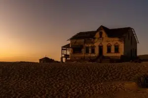 An old abandoned house in the desert with a golden sunset background