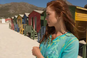 Side view of thoughtful gorgeous young Caucasian woman standing on the beach. She is enjoying her holiday