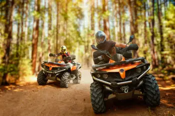 wo atv riders in helmets, speed race in forest, front view. Riding on quad bike, extreme sport and travelling, quadbike offroad adventure